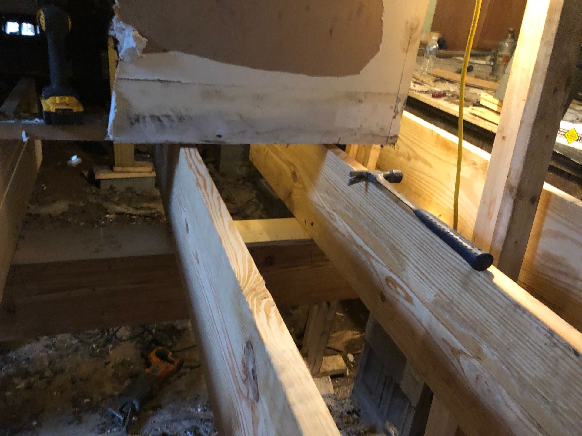 Wooden construction framing with beams and a wall opening in a dimly lit interior.