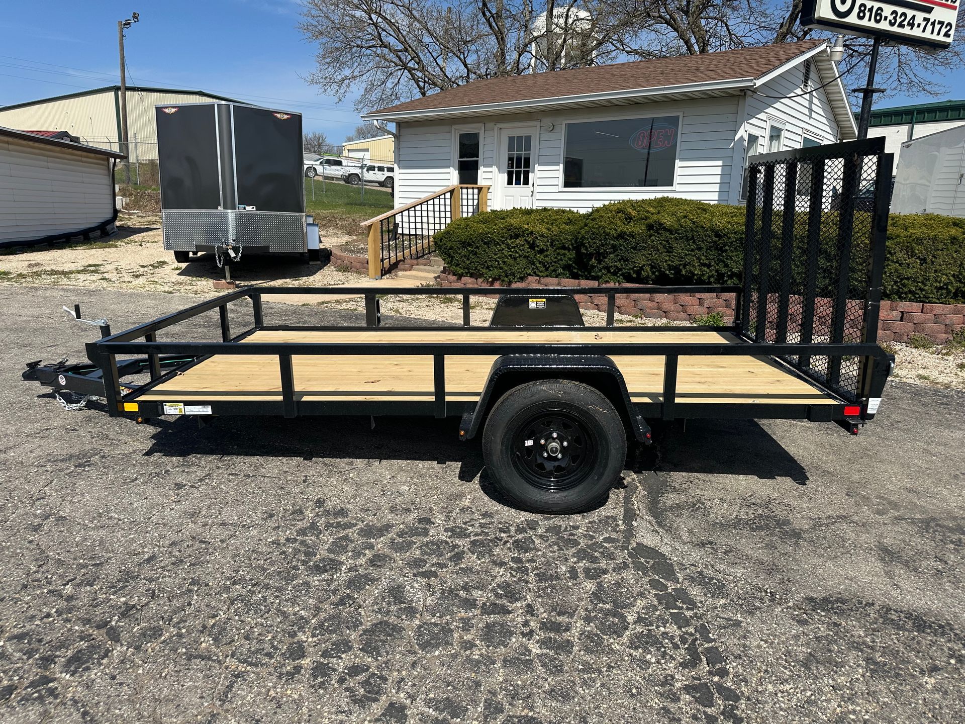 Aluminum utility trailer with wood floor, parked in front of a building