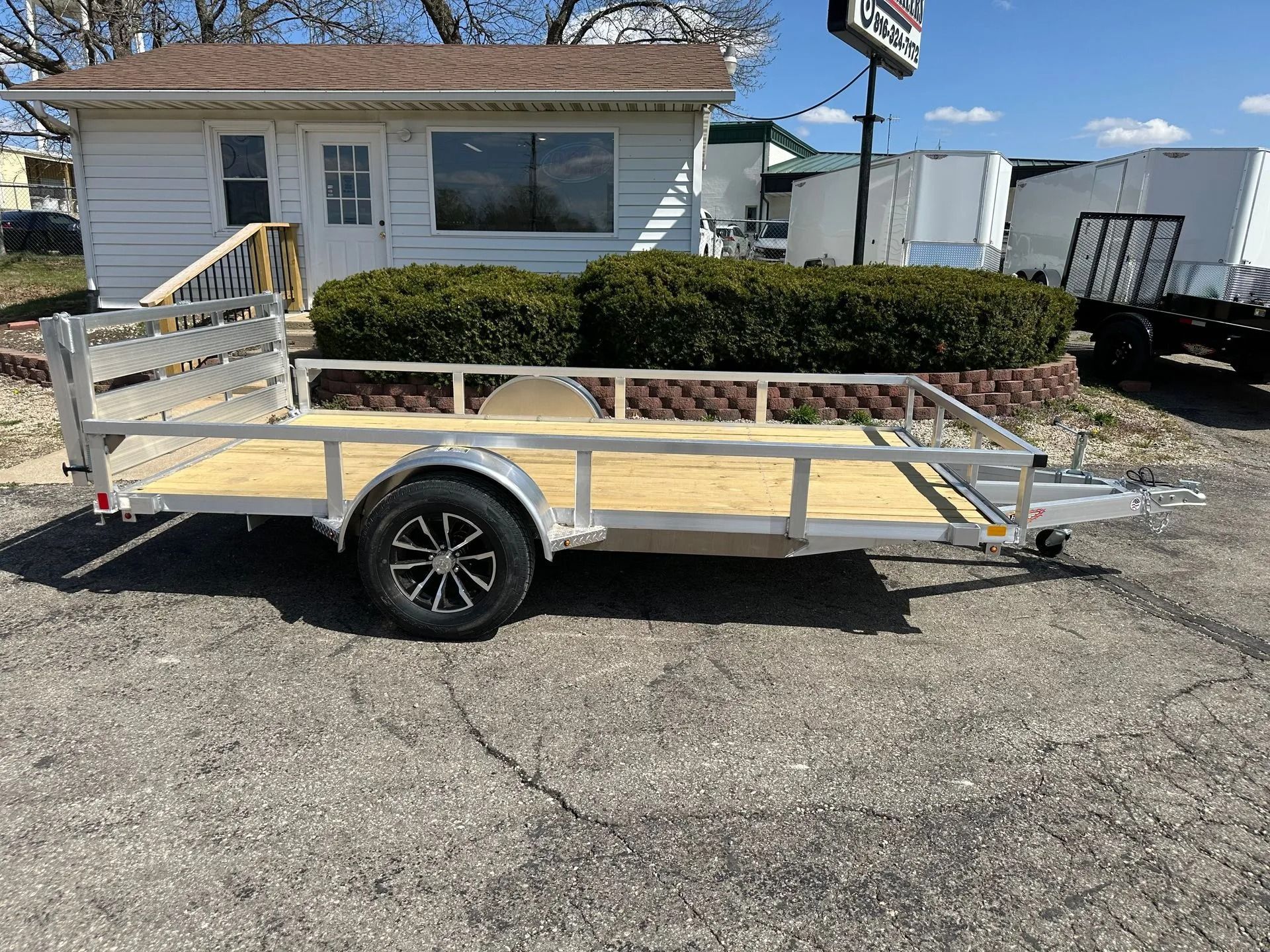 Aluminum utility trailer parked in front of a building.