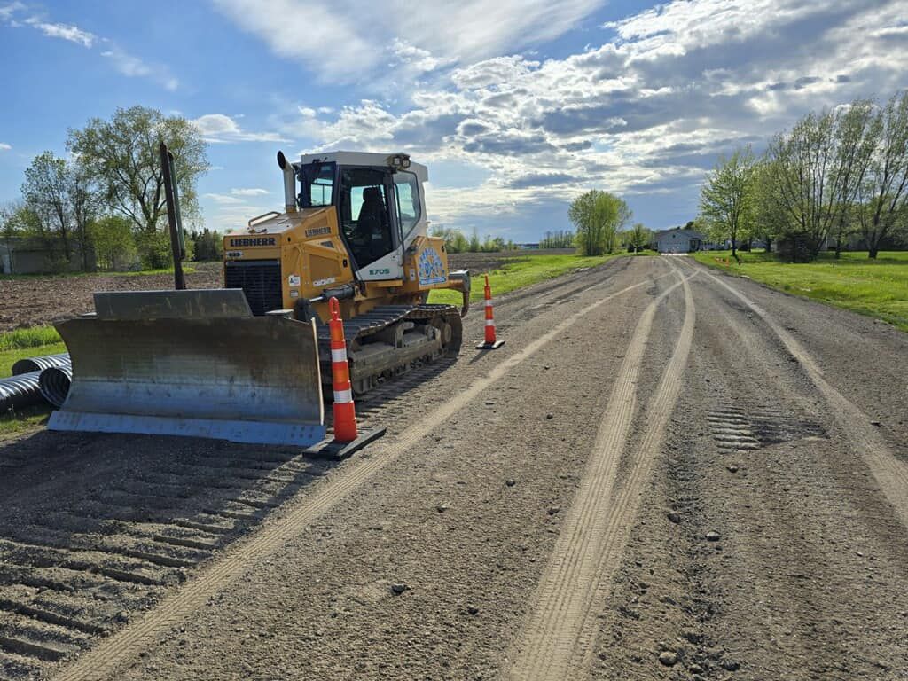 A bulldozer is sitting on the side of a dirt road.