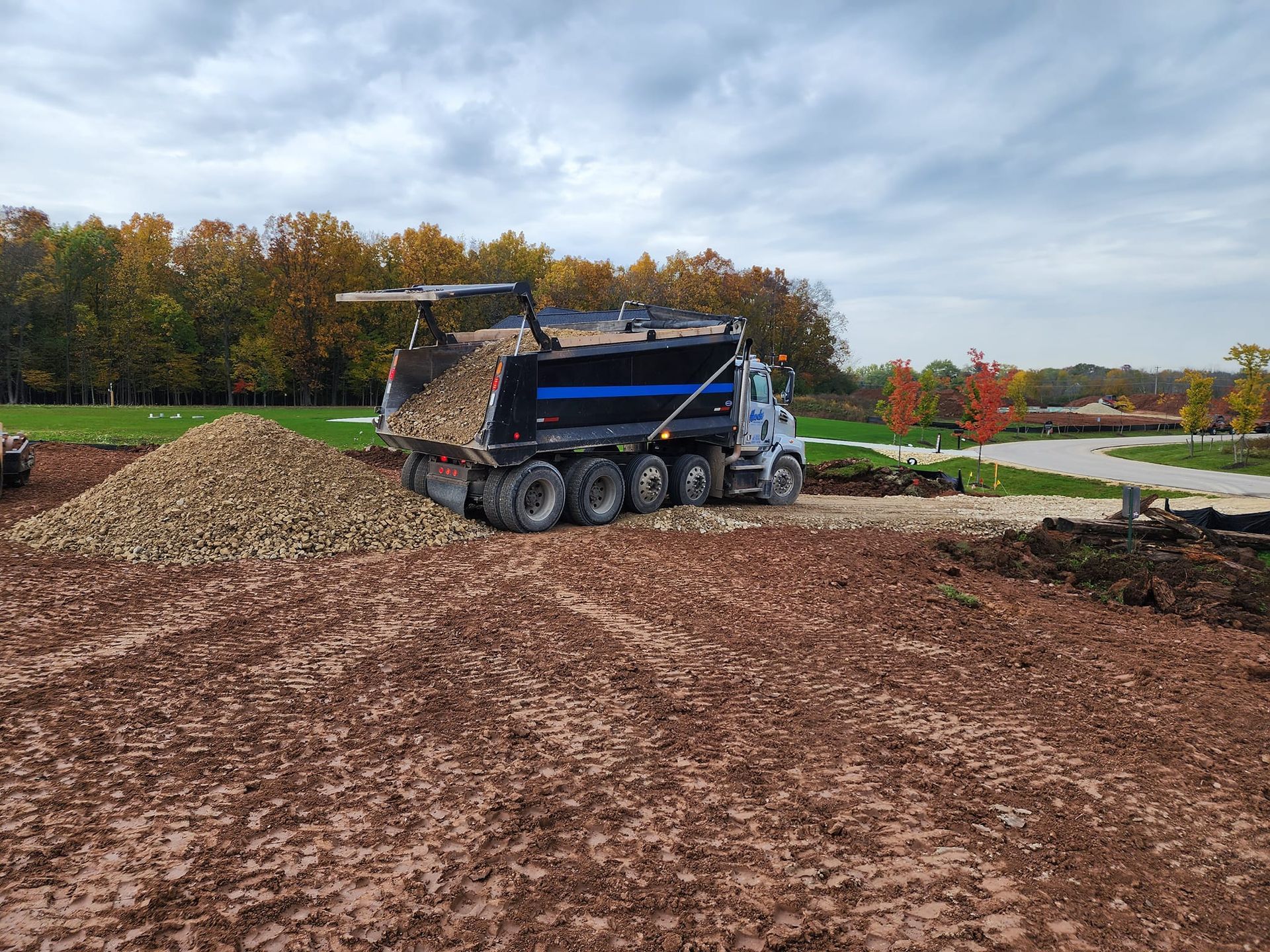 A dump truck is driving through a dirt field.
