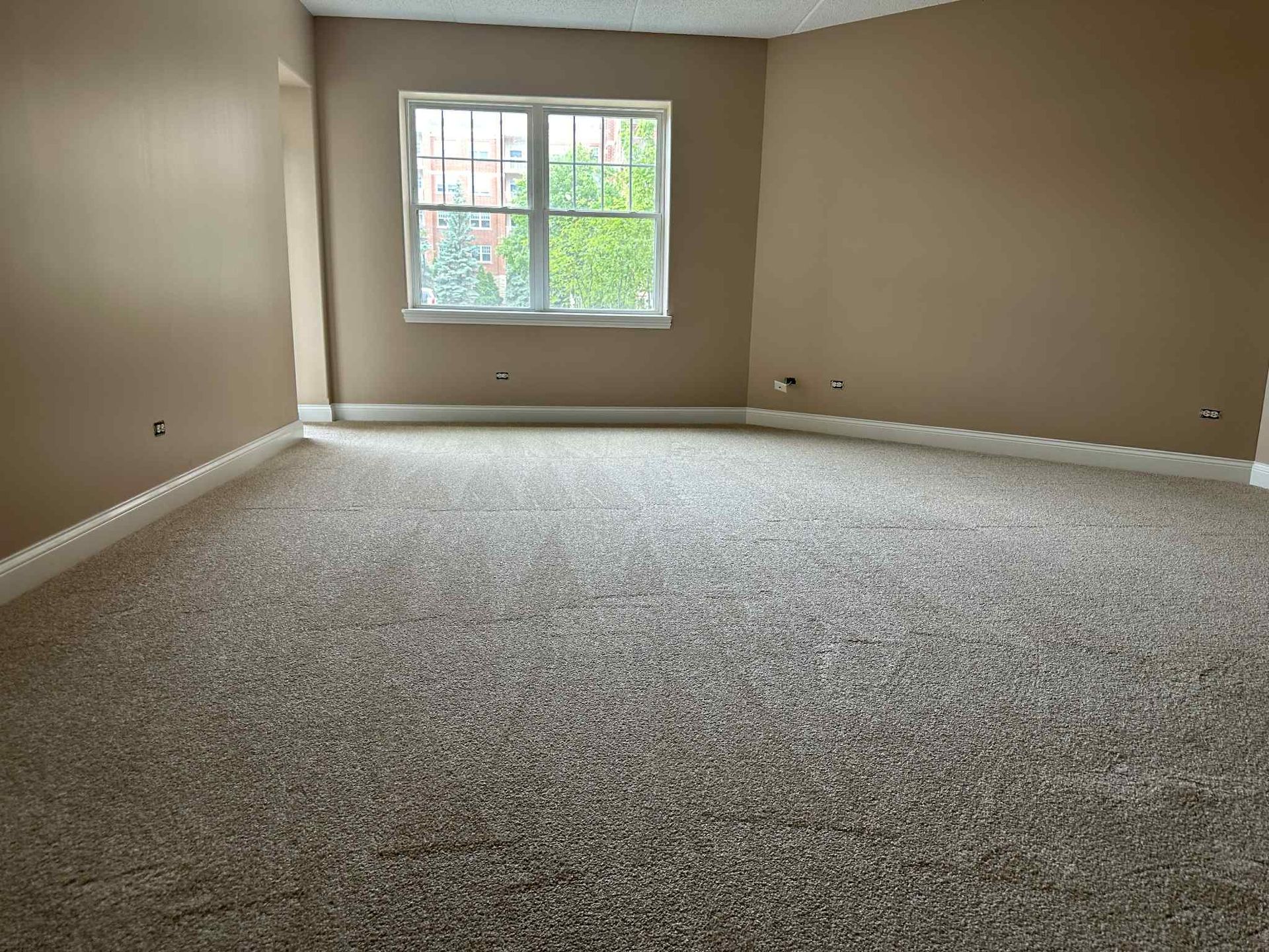 Empty room with neutral walls, light-colored carpet, and a window.