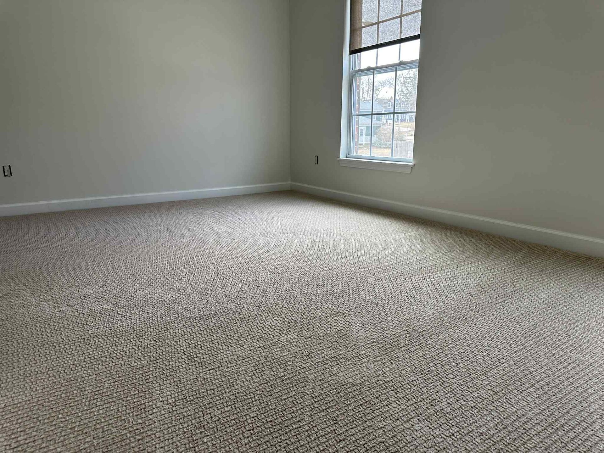 Empty room with beige carpet, light walls, and a window with blinds.