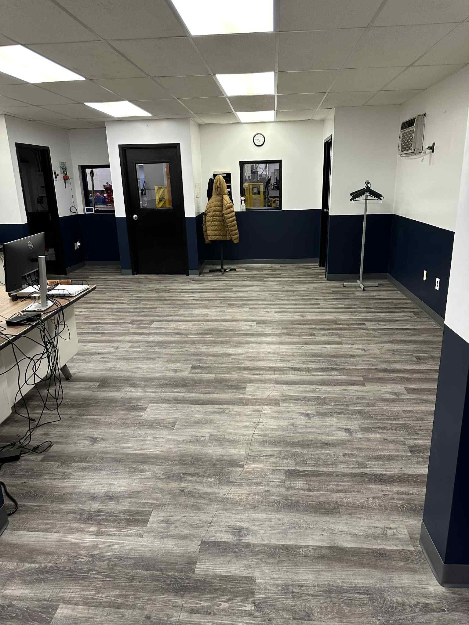 An office interior with wood-look flooring, dark blue and white walls, and a coat rack.