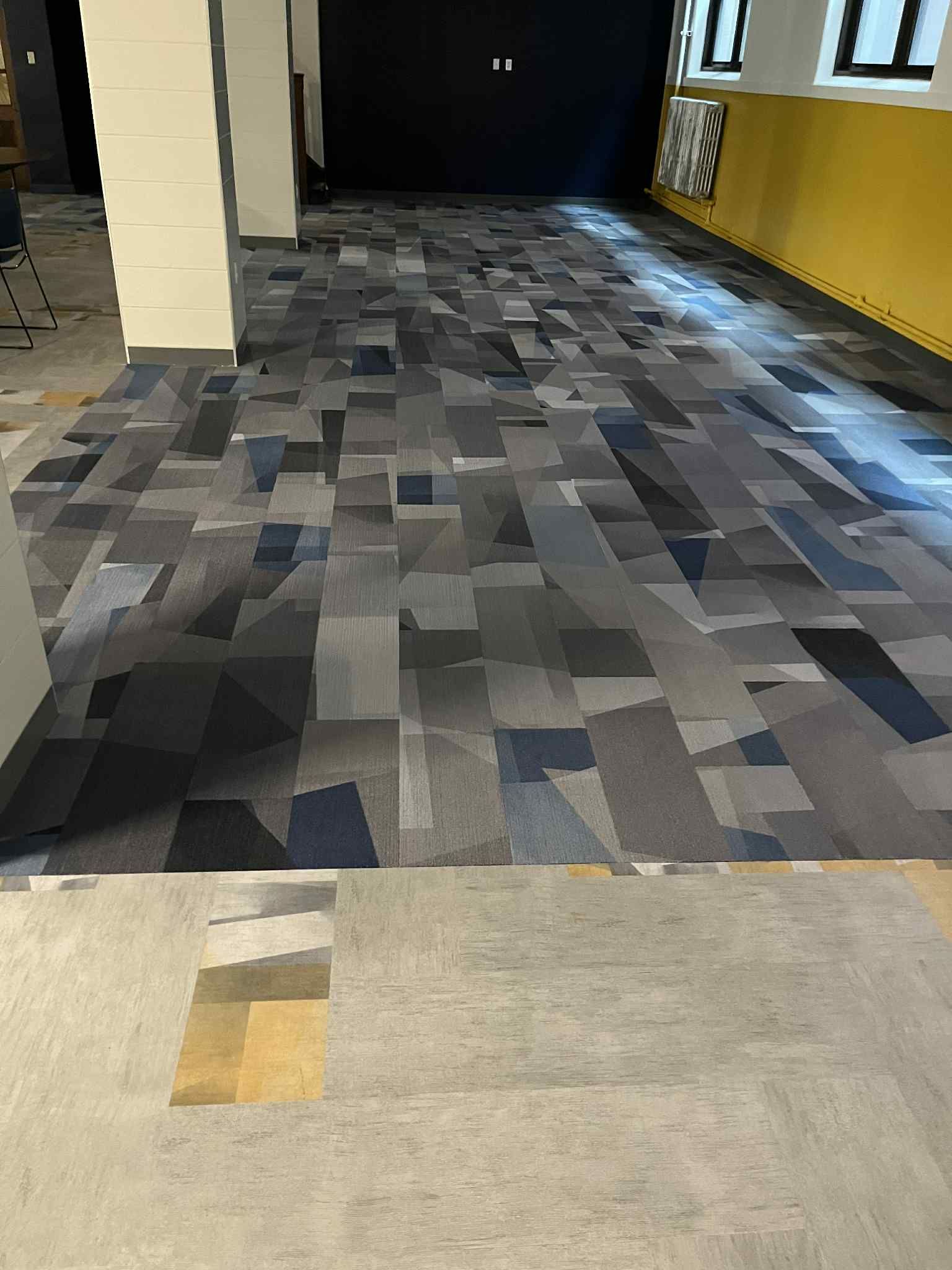 Room with newly installed geometric patterned carpet; unfinished flooring in foreground.
