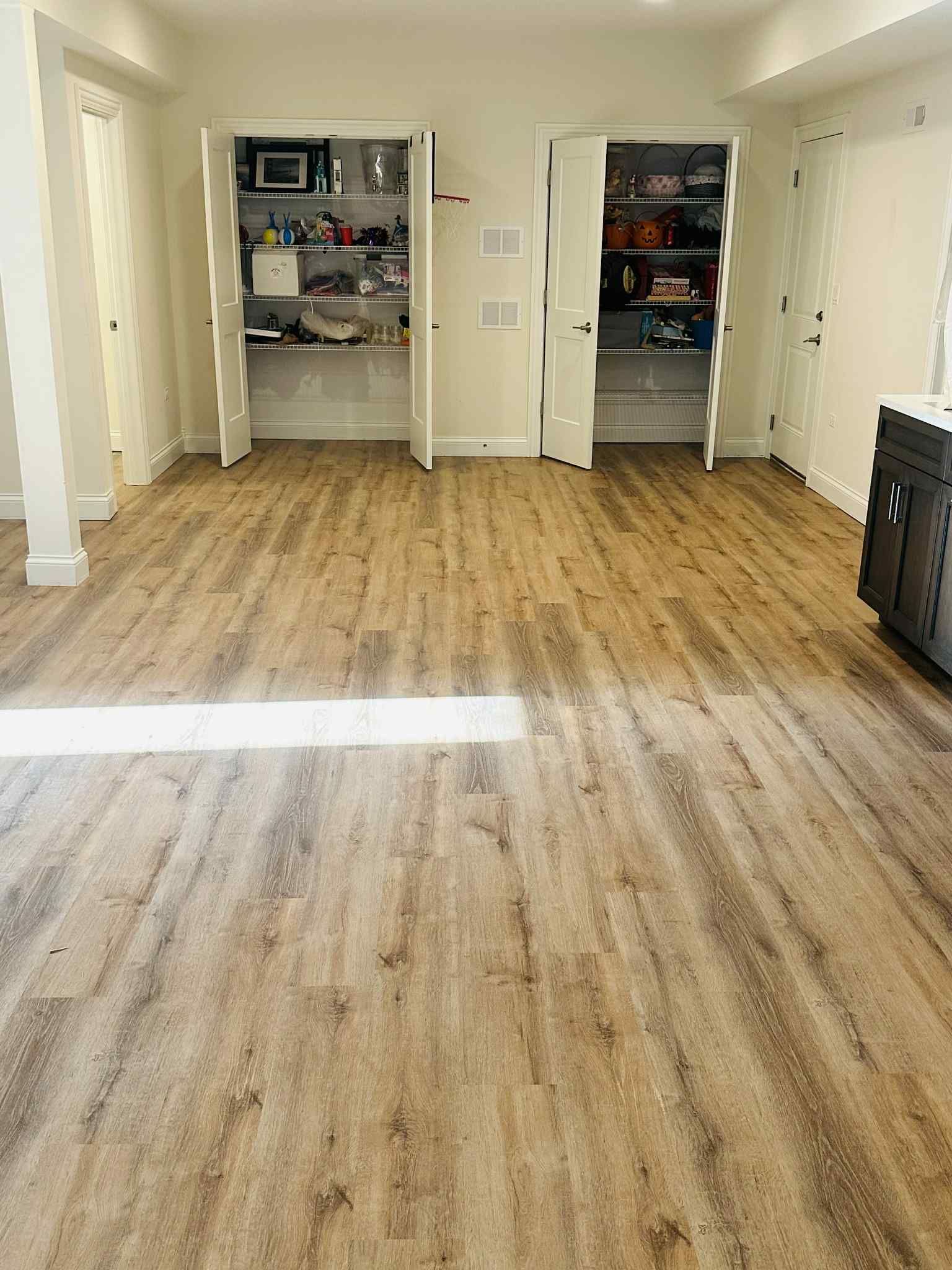 Wooden floor with two open pantry cabinets filled with items. Bright room, natural light.