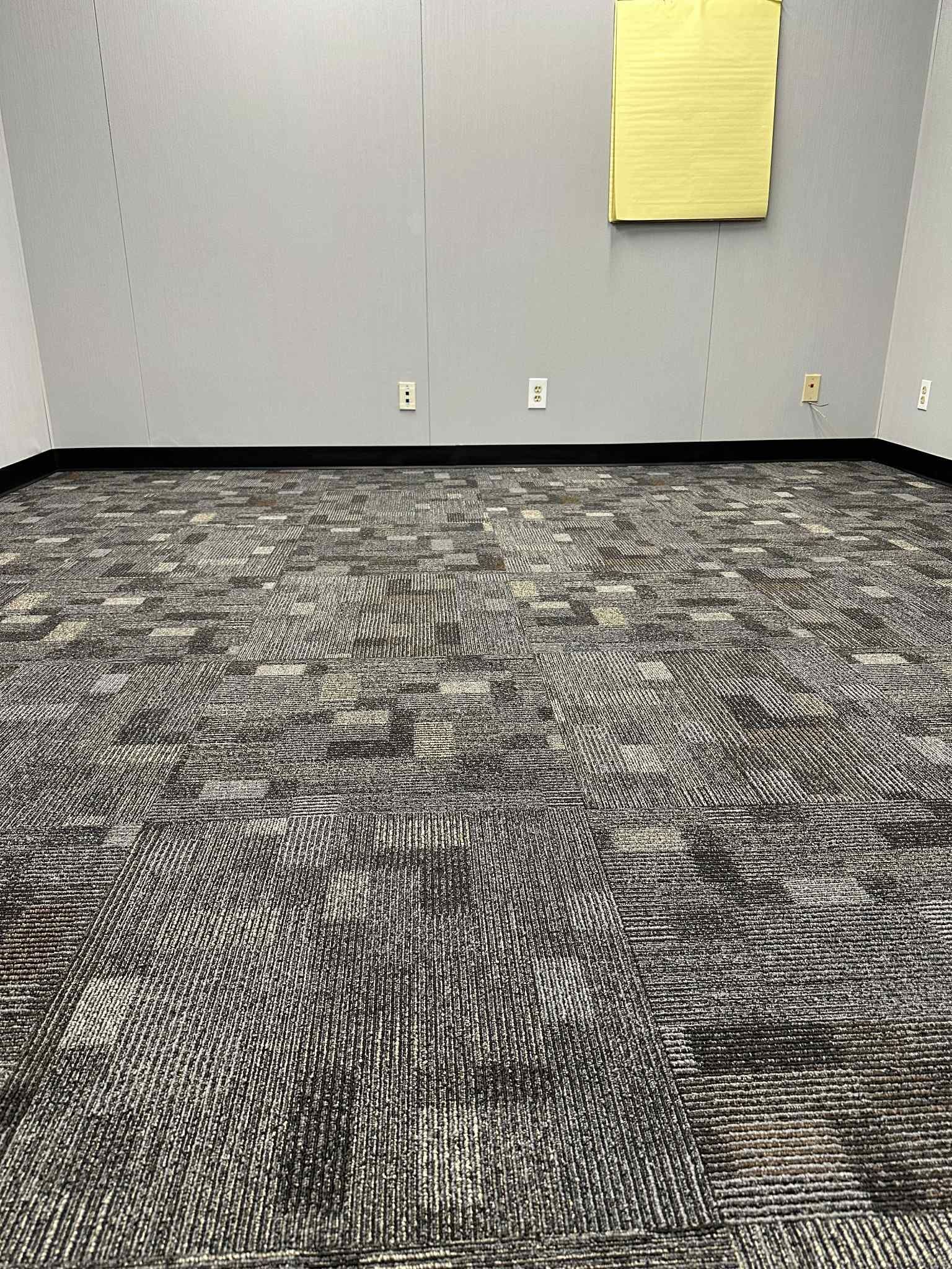 Empty room with patterned carpet, gray walls, and yellow sticky notes.
