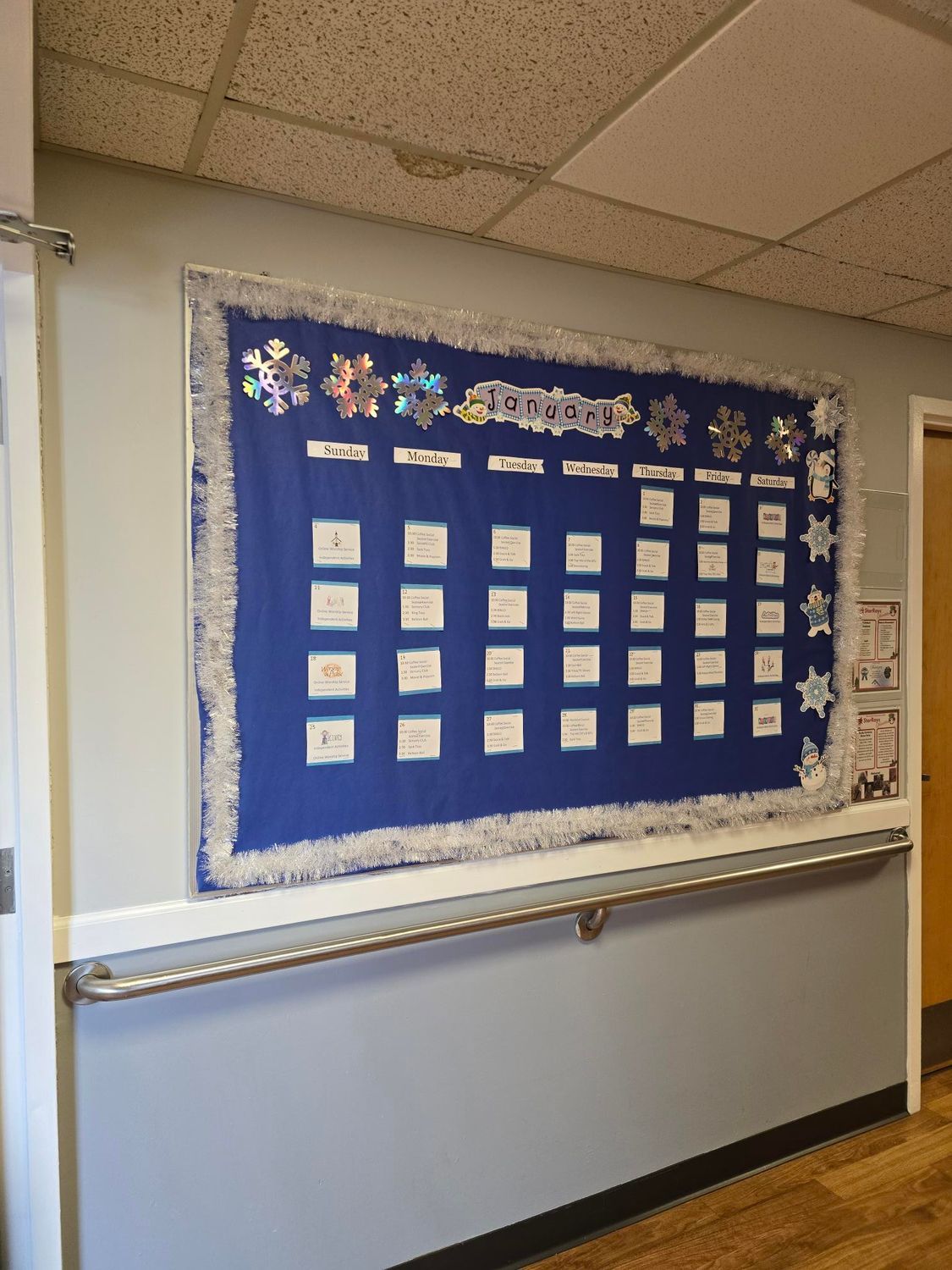 Bulletin board with blue background and white writing, decorated with snowflakes.