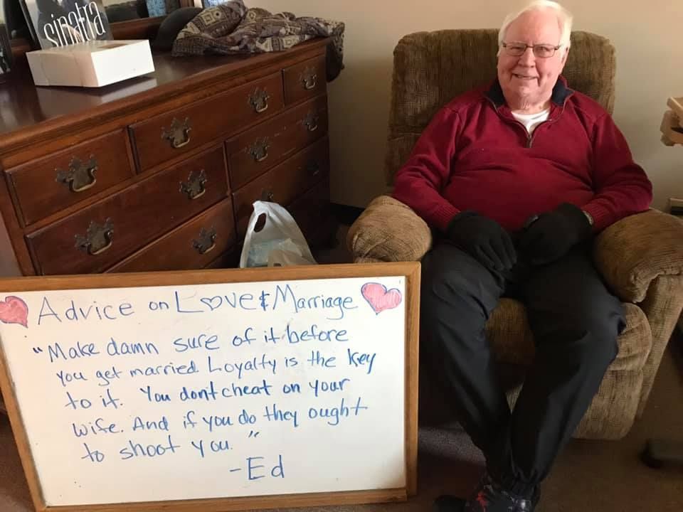 Elderly man in a chair with sign: 