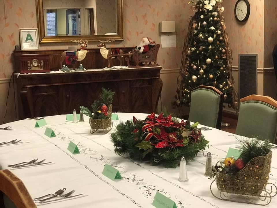 Dining room set for Christmas with a decorated tree, centerpiece, and table settings.