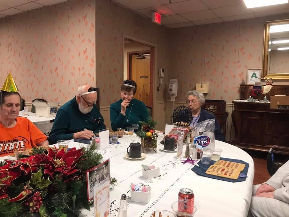People seated around a decorated table; celebration in an interior space.