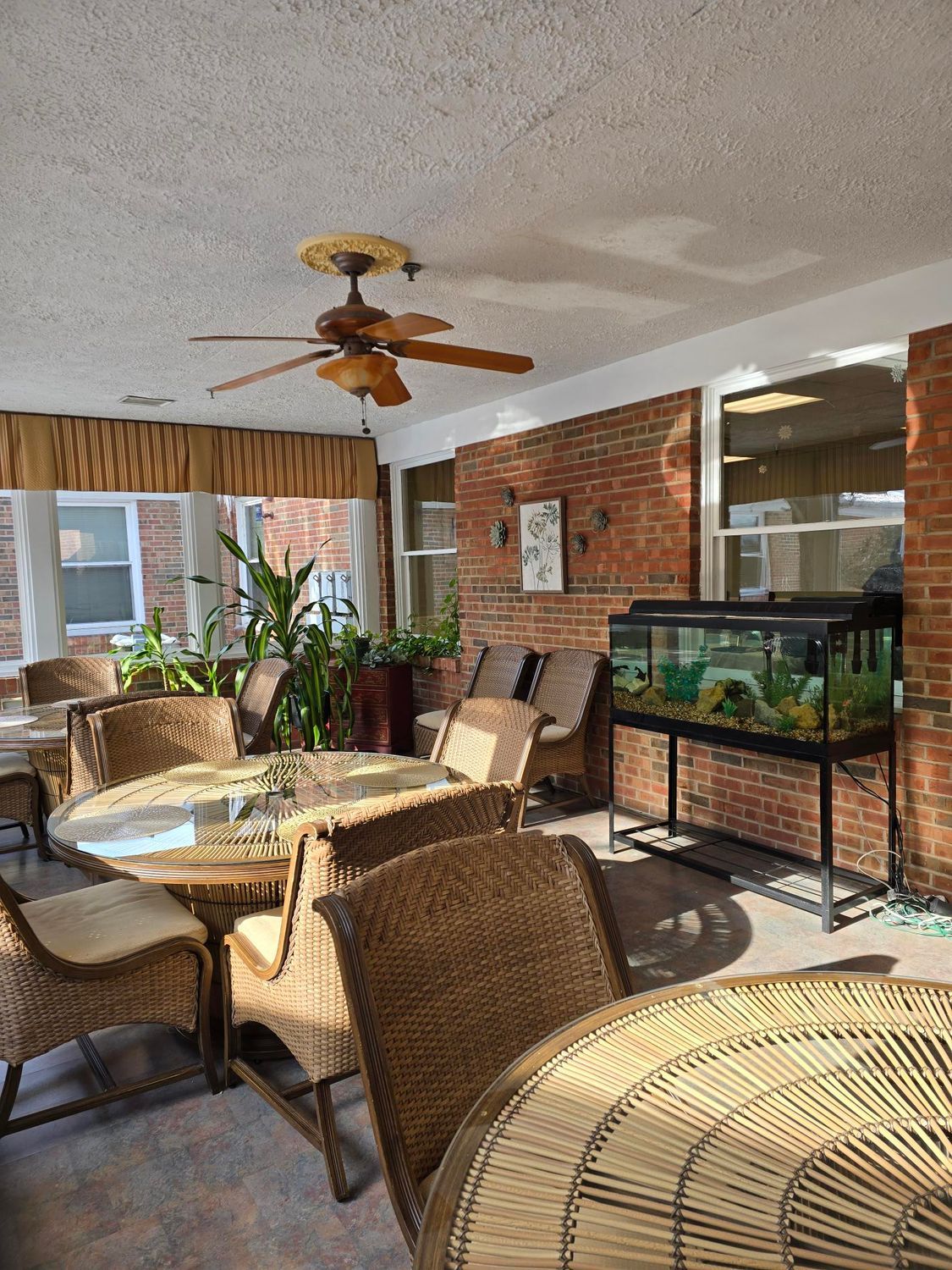 Sunroom with wicker furniture, brick walls, a ceiling fan, and an aquarium.