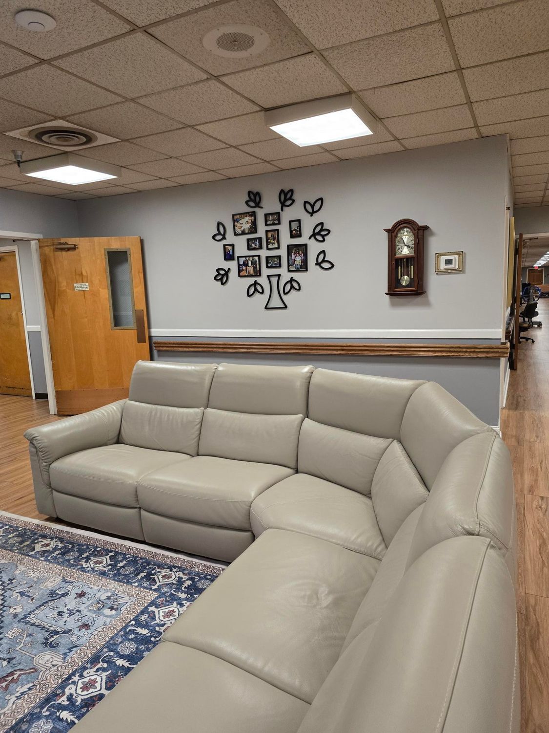 Gray sectional sofa in a waiting area with a wall decoration and clock.