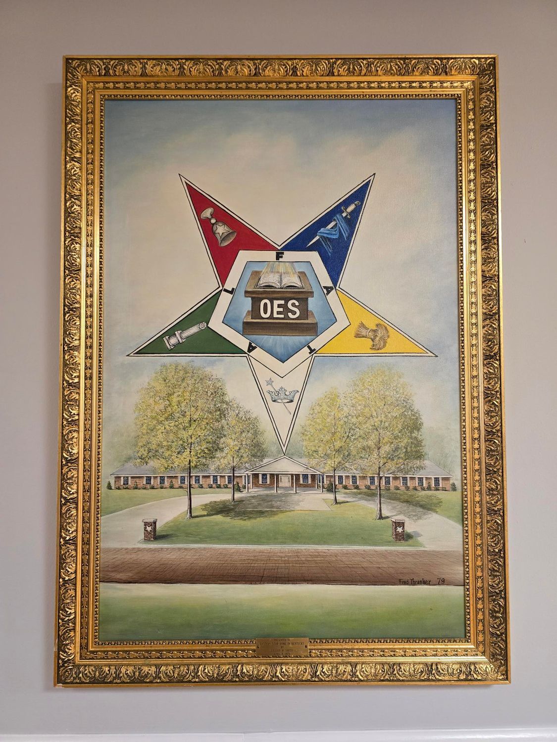 Framed painting of an Eastern Star symbol atop a building with trees, in a gold frame.