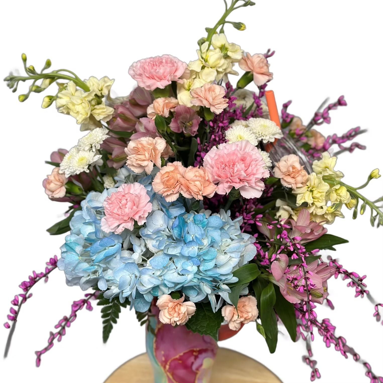 Close-up of a bouquet of colorful flowers including blue hydrangea and pink carnations.