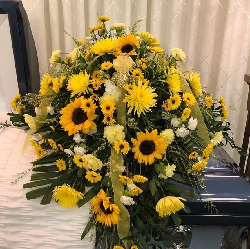 Floral arrangement of sunflowers and yellow flowers on a casket.