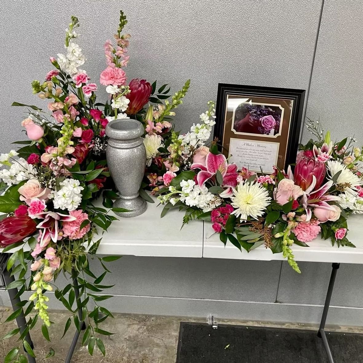 Floral arrangement with an urn and framed photo on a table.