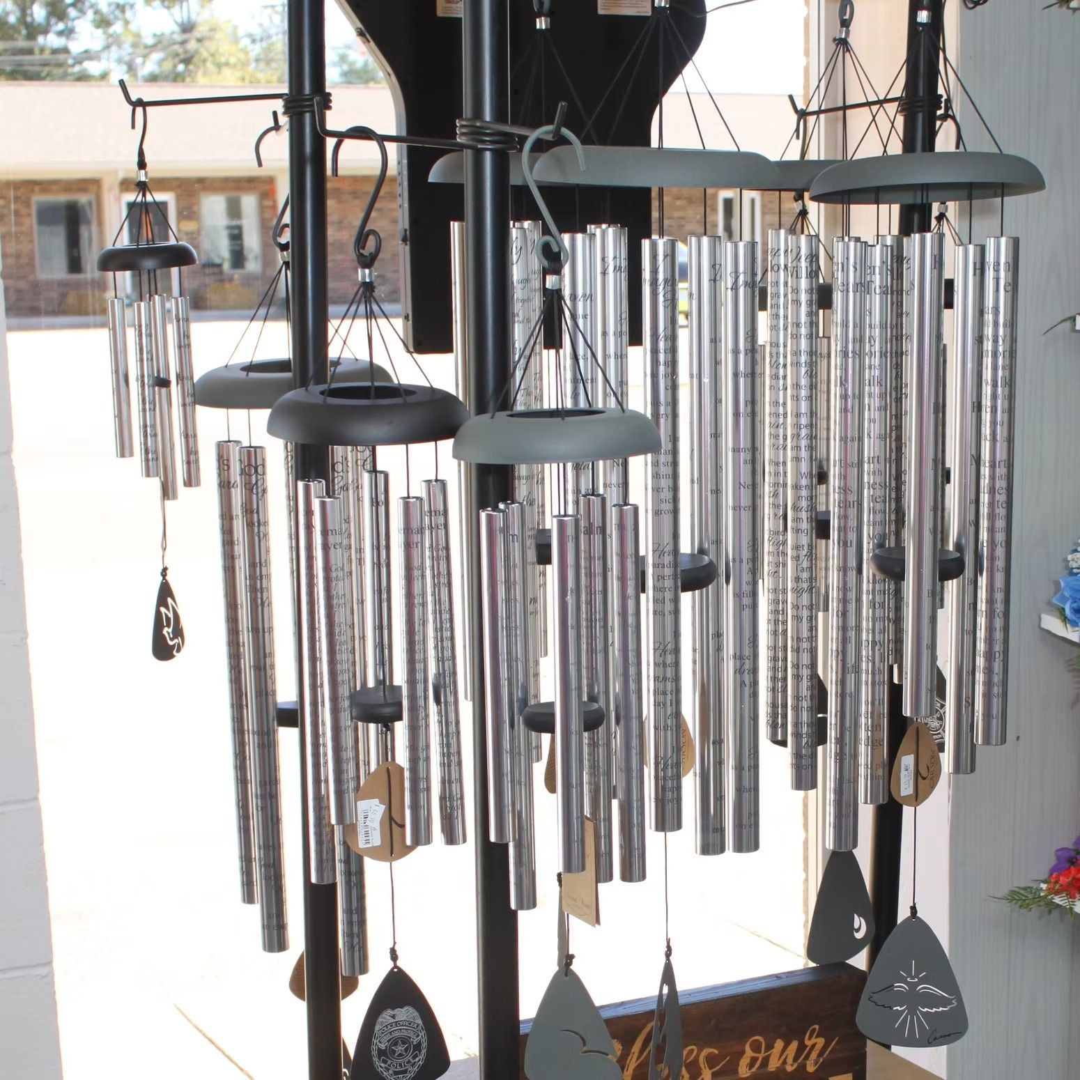 Wind chimes displayed in a store, silver tubes hanging from black supports, tags attached.