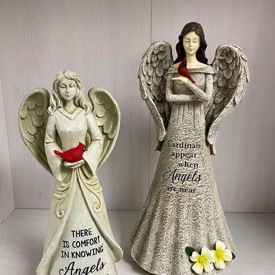 Two angel statues holding red cardinals. One reads