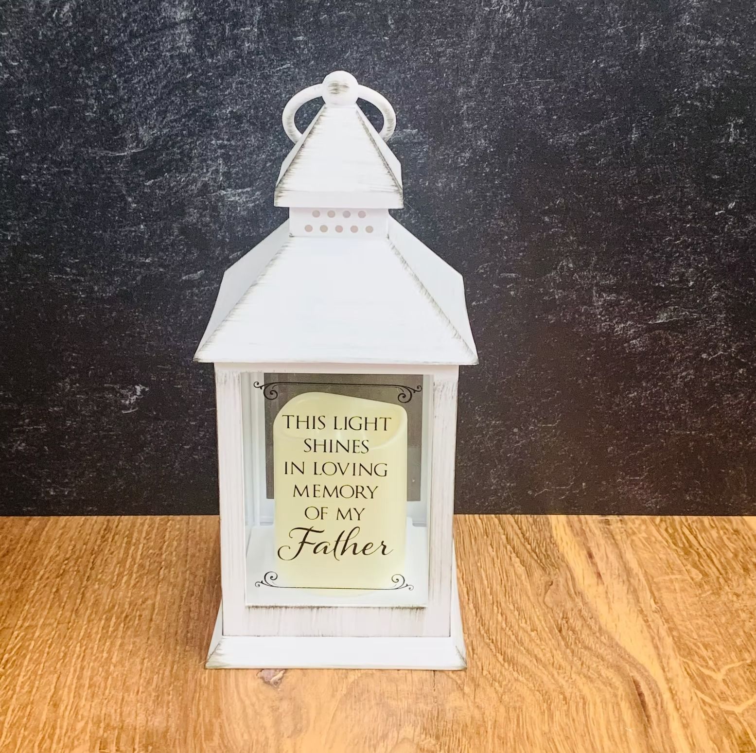 White lantern with a candle inside that reads,