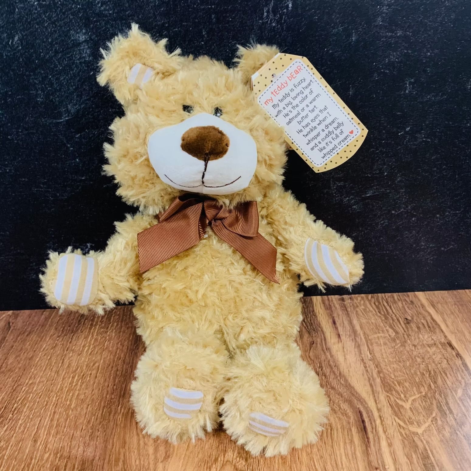 Tan teddy bear with brown bow and tag.