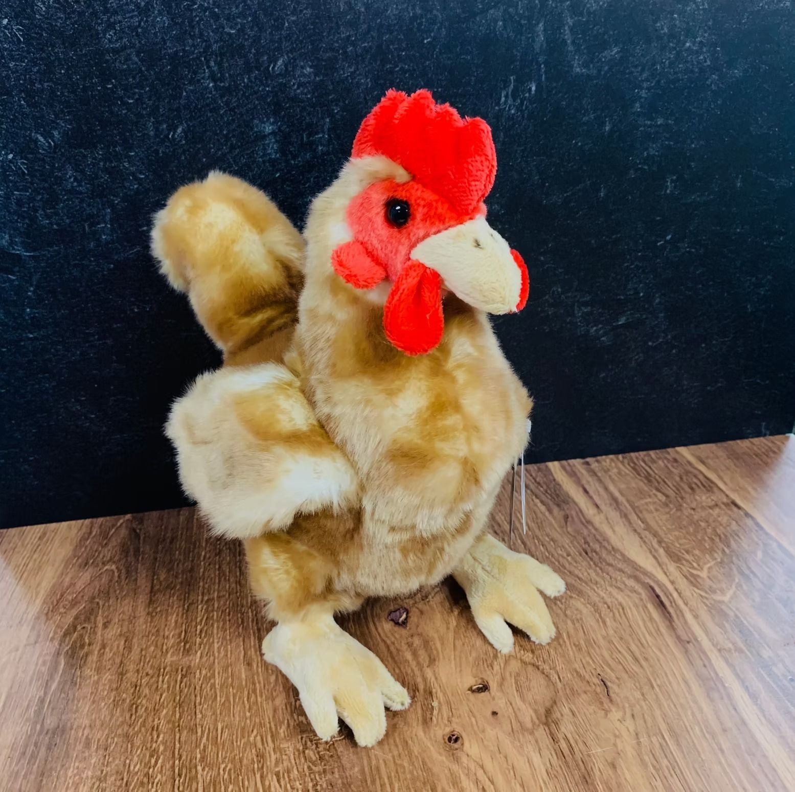 Stuffed toy chicken with brown and tan feathers, red comb and wattle, on a wooden surface.