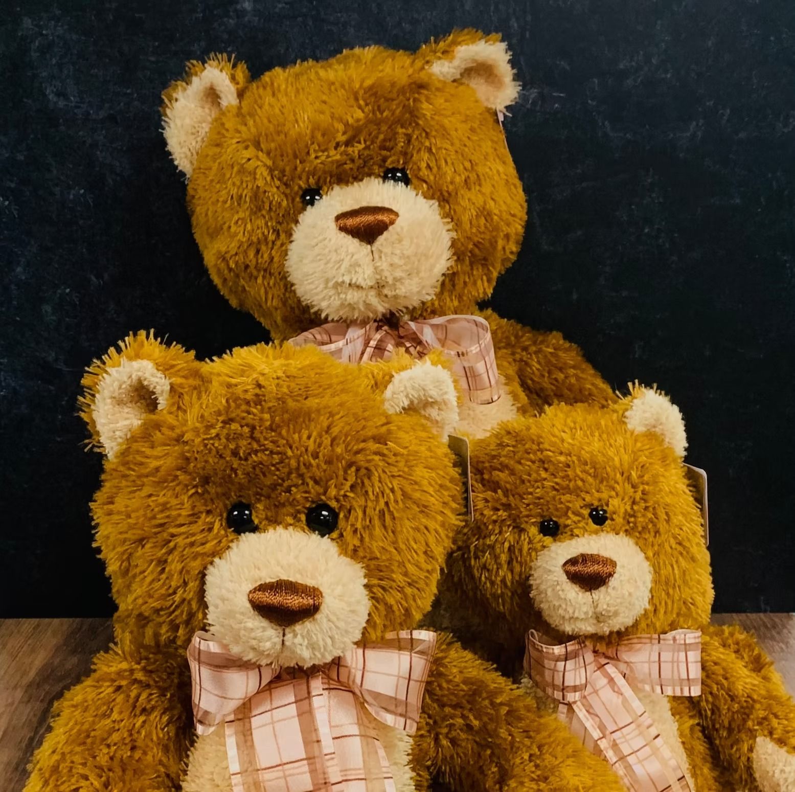 Three brown teddy bears with pink plaid bows.