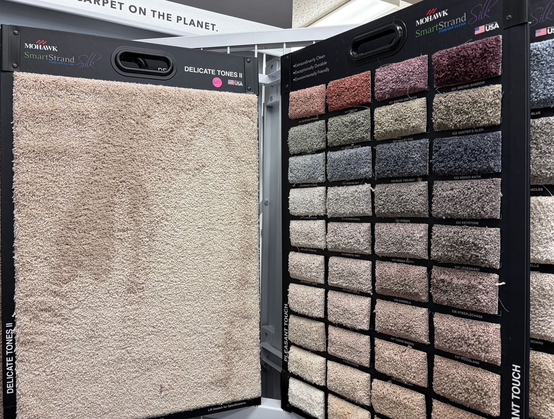 Carpet samples in various neutral shades displayed on a rack.