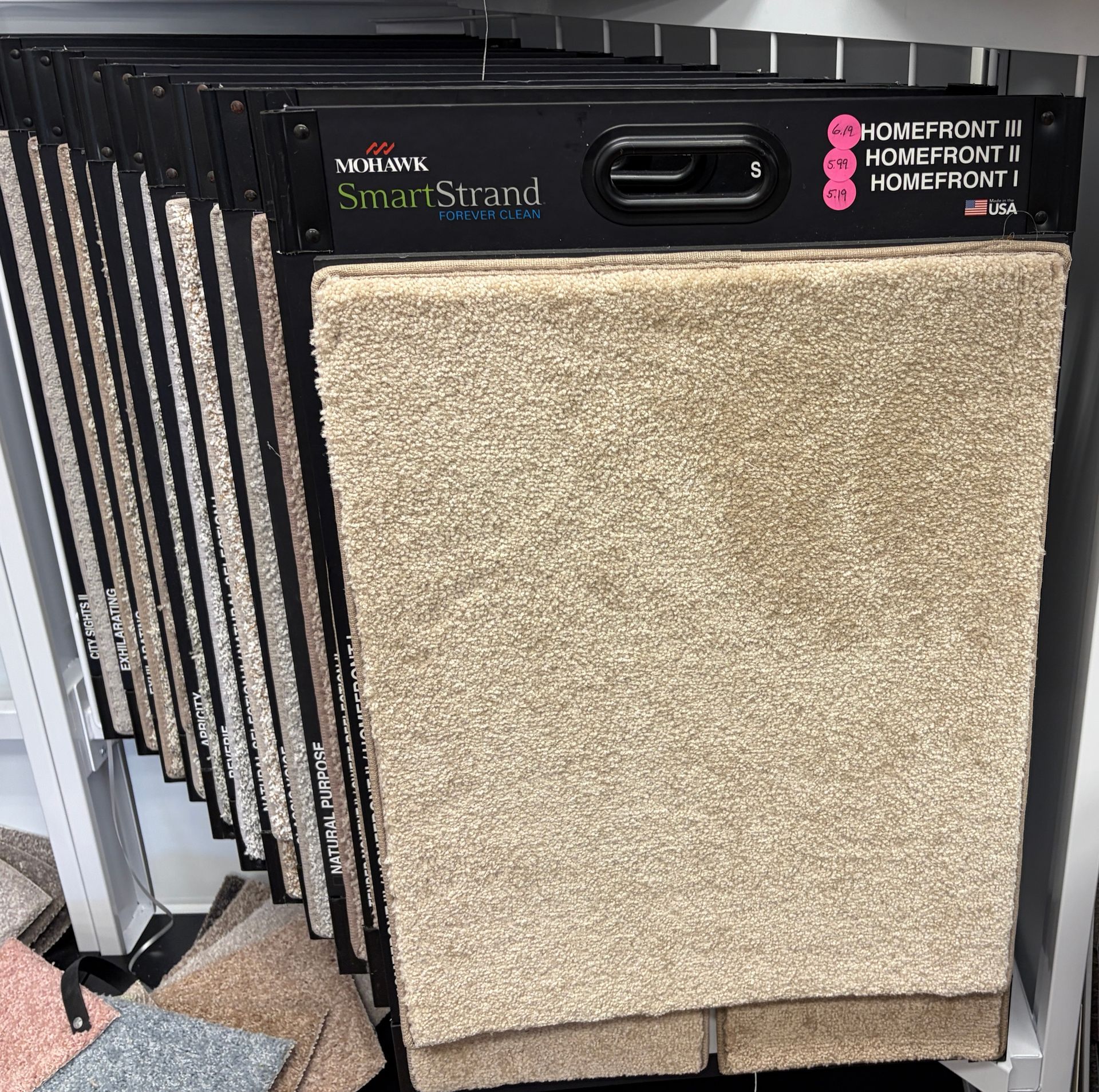 Carpet samples displayed on a rack. Tan, textured carpet samples are visible.