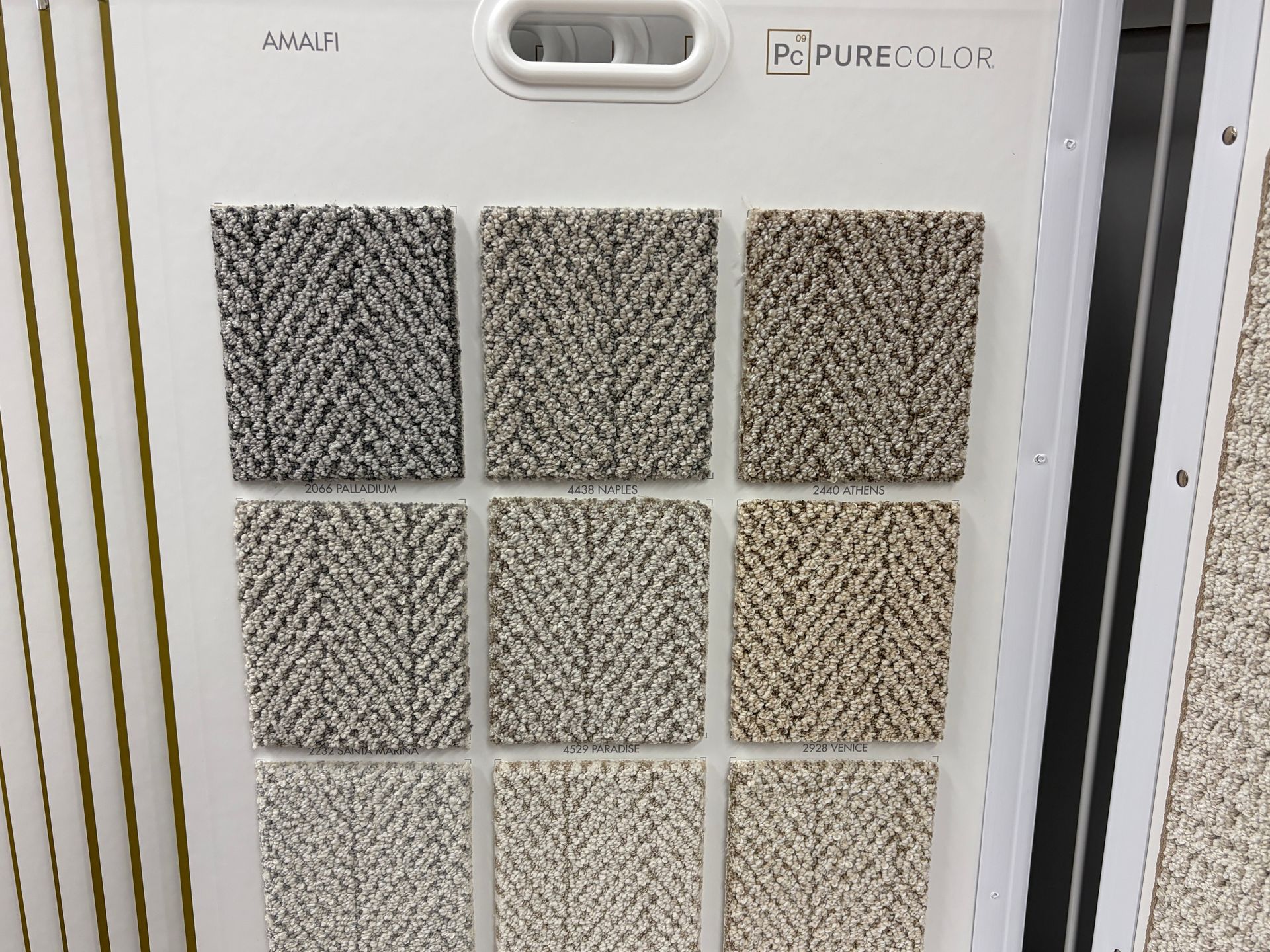 Carpet sample board with nine rectangular swatches in neutral colors and patterned texture.