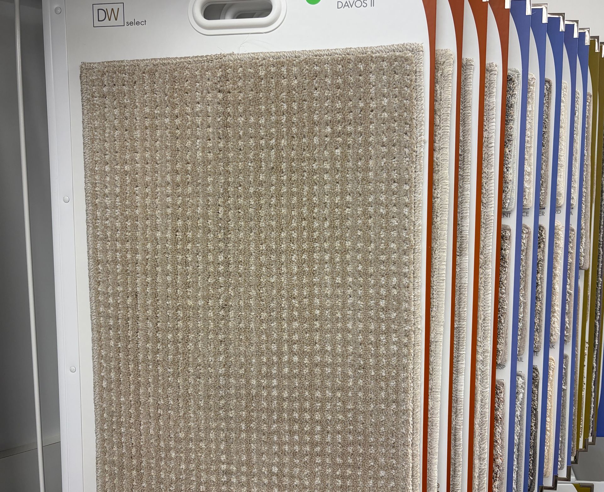 Carpet samples in various neutral colors, displayed in a showroom setting.