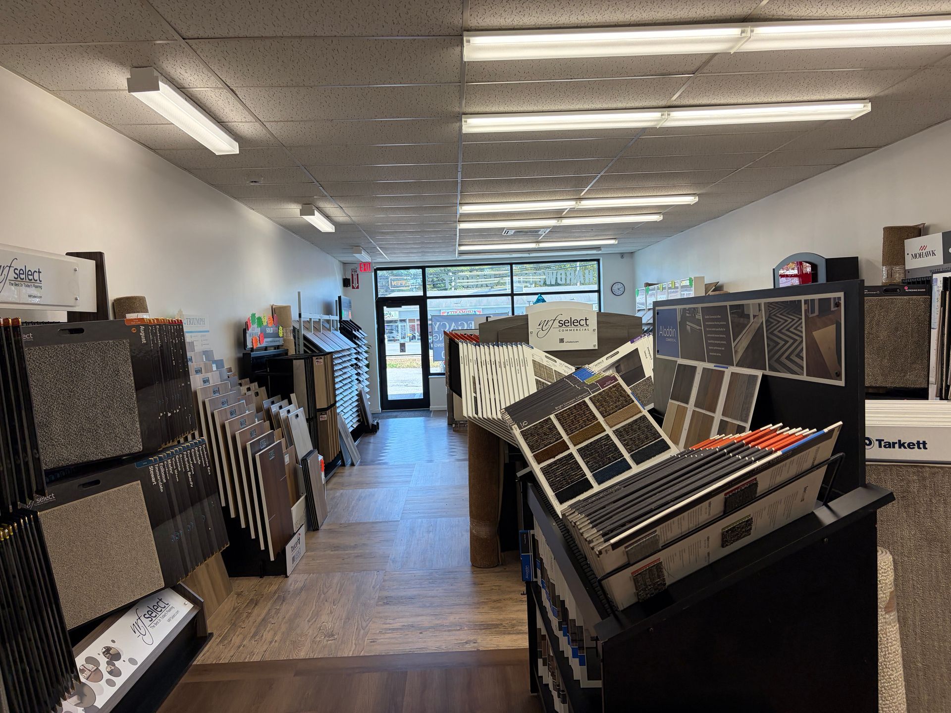 Carpet and flooring showroom with sample displays and open doorway.