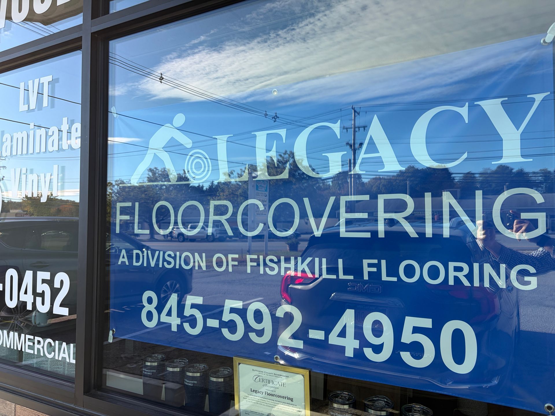 Window sign for Legacy Floorcovering with phone number, a division of Fishkill Flooring.