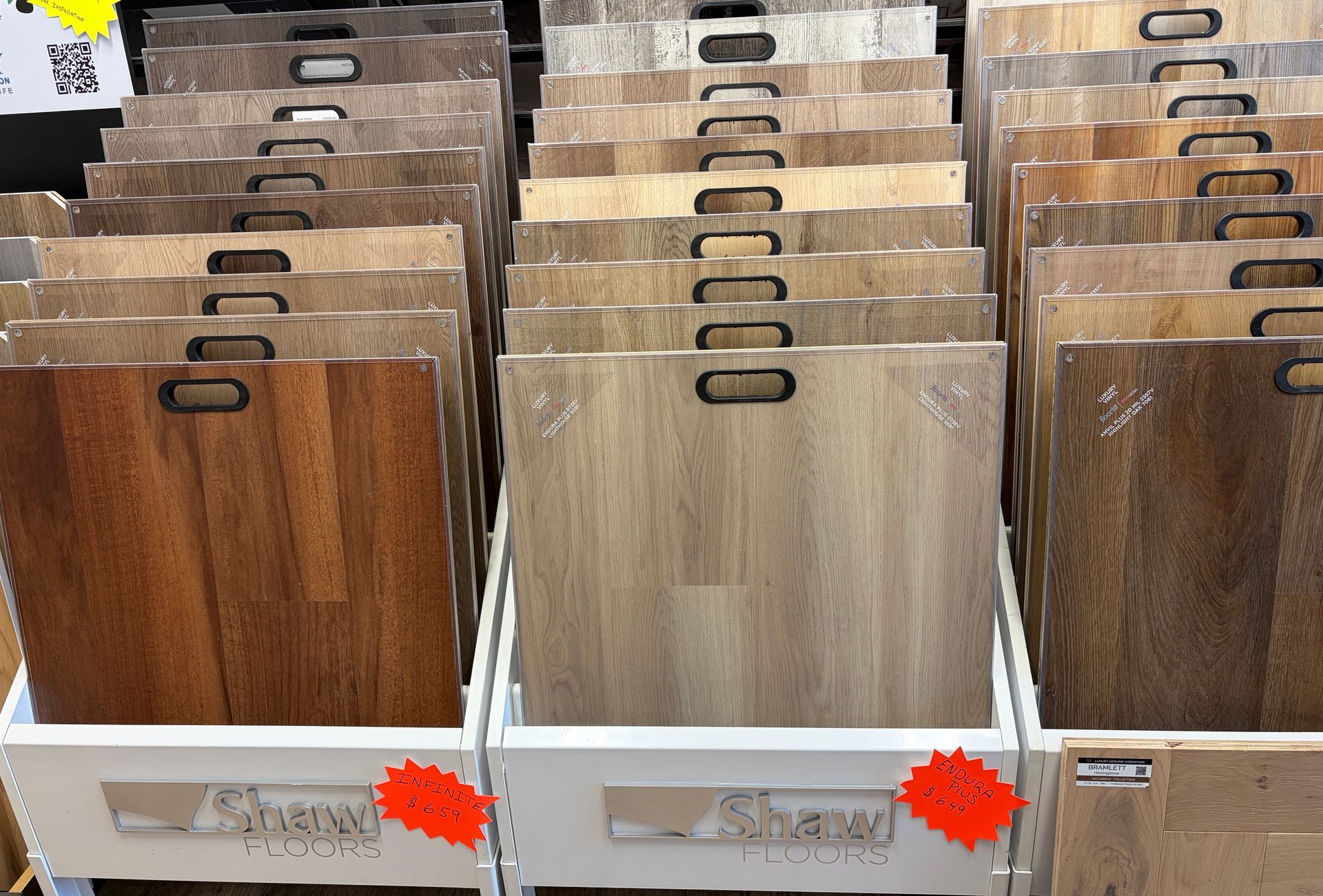 Display of various wood flooring samples in a store, showcasing different colors and patterns.