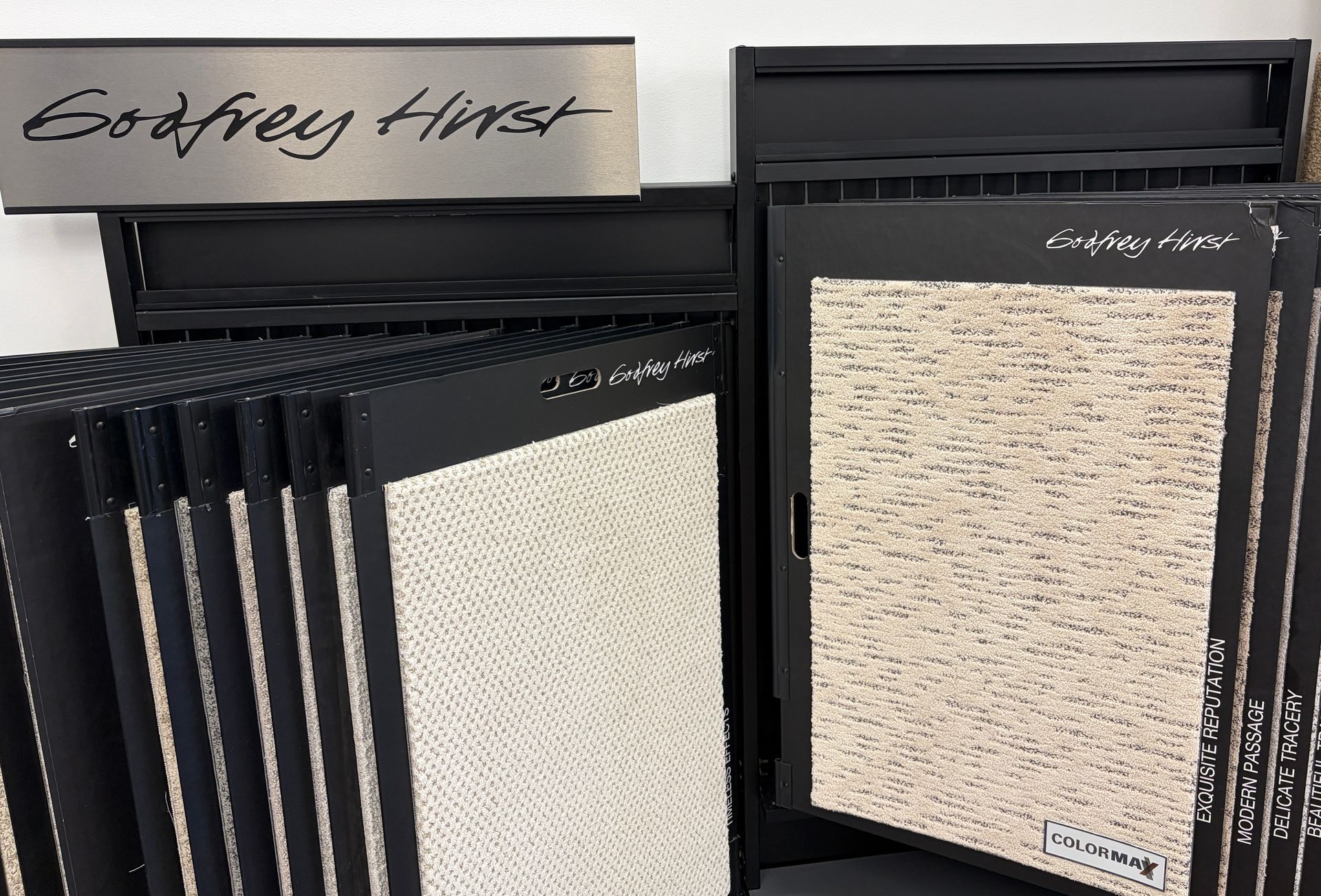 Display of Godfrey Hirst carpet samples on black stands.