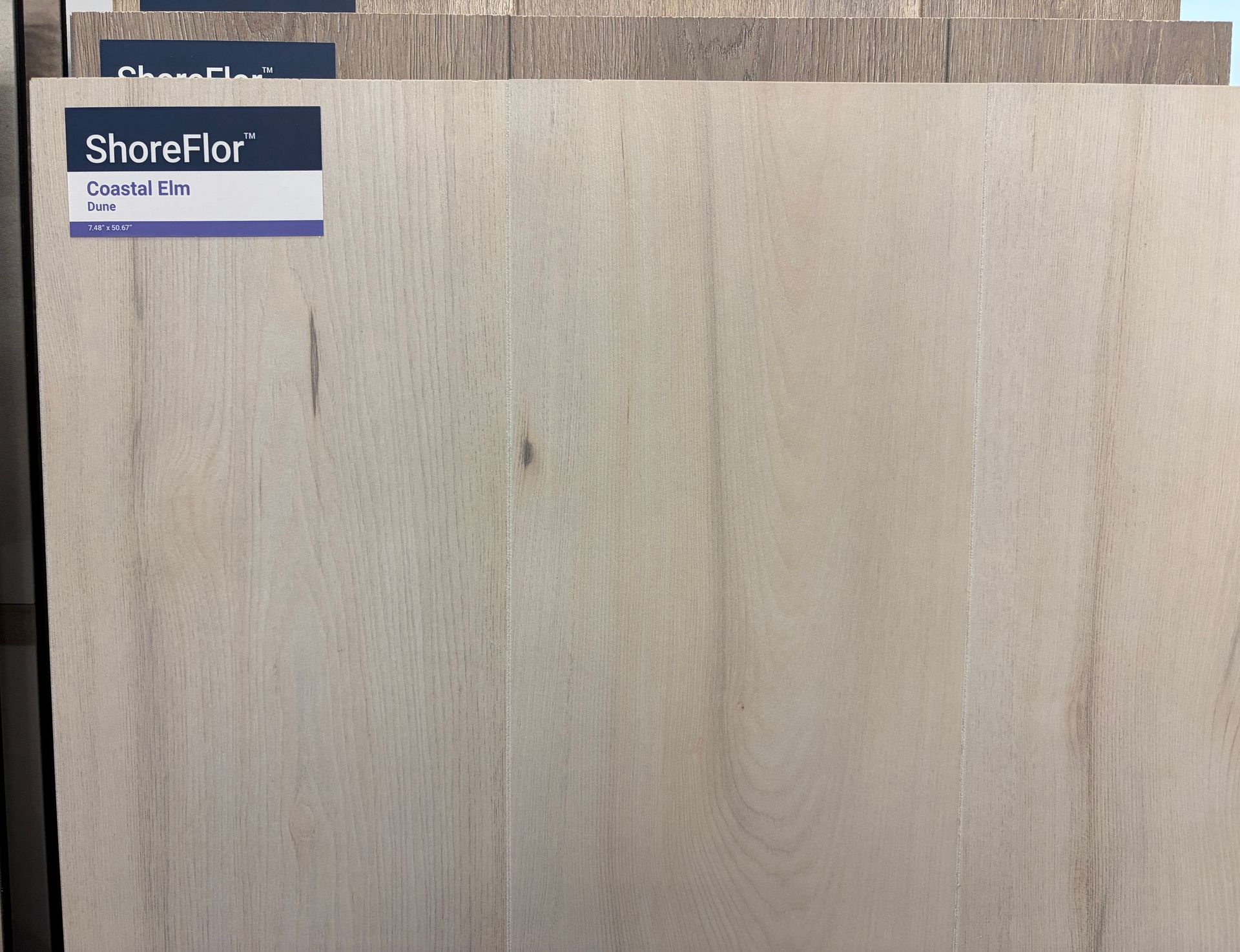 Light wood grain flooring sample with ShoreFlor label.