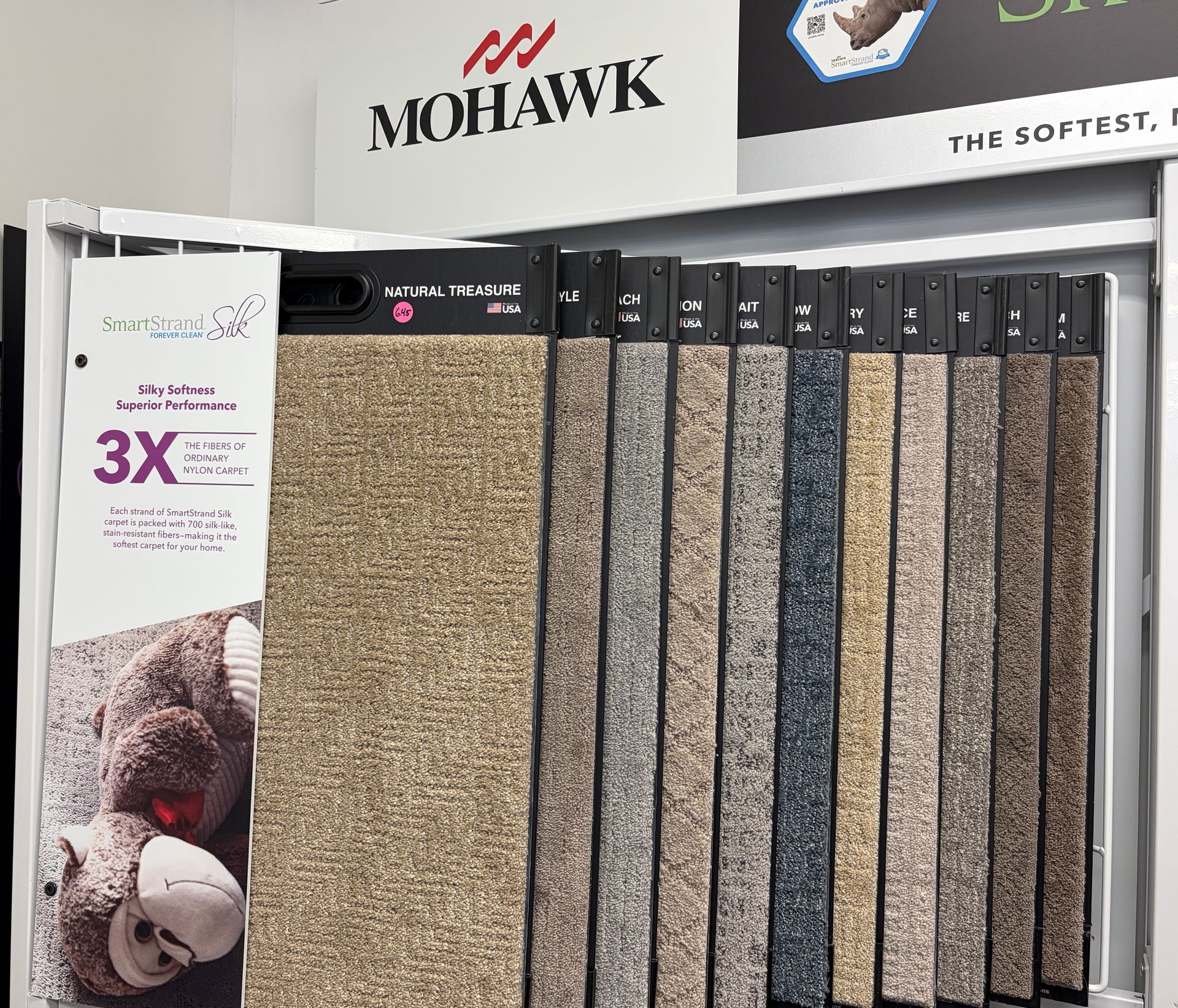 Carpet samples in various colors displayed on a rack, Mohawk logo visible above.