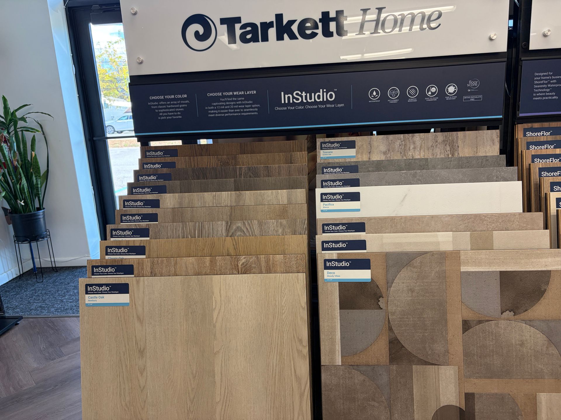 Display of Tarkett Home flooring samples in a store. Various tile colors and patterns are shown.