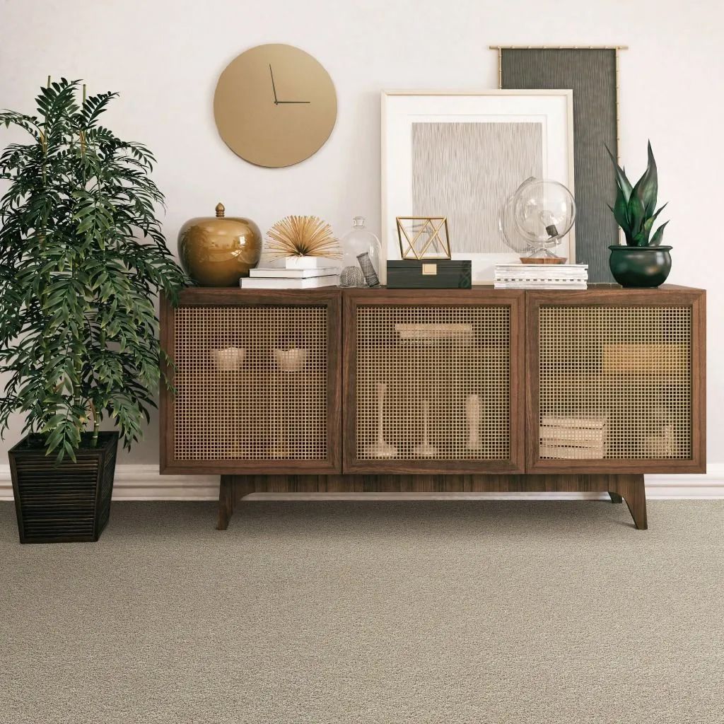 Wooden cabinet with decor, including a clock and plants, against a white wall and tan carpet.