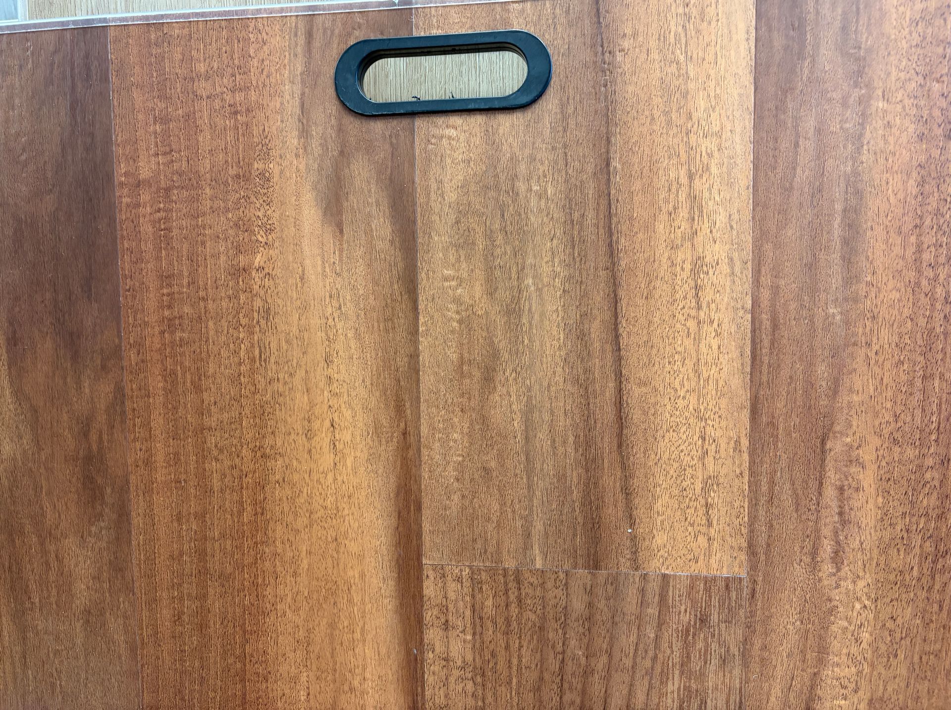 Brown wood-look flooring sample with a black handle at the top.