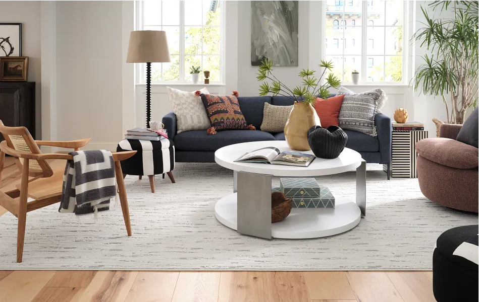 Living room with blue sofa, white coffee table, wooden chair, and large windows.
