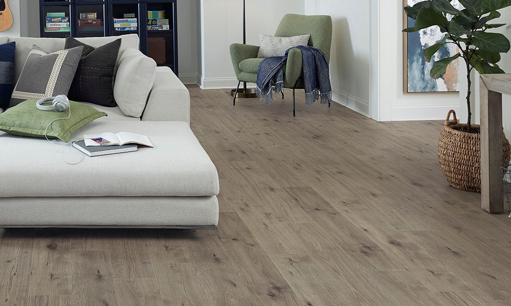 Living room with light wood-look flooring, a white sofa, and a green armchair.