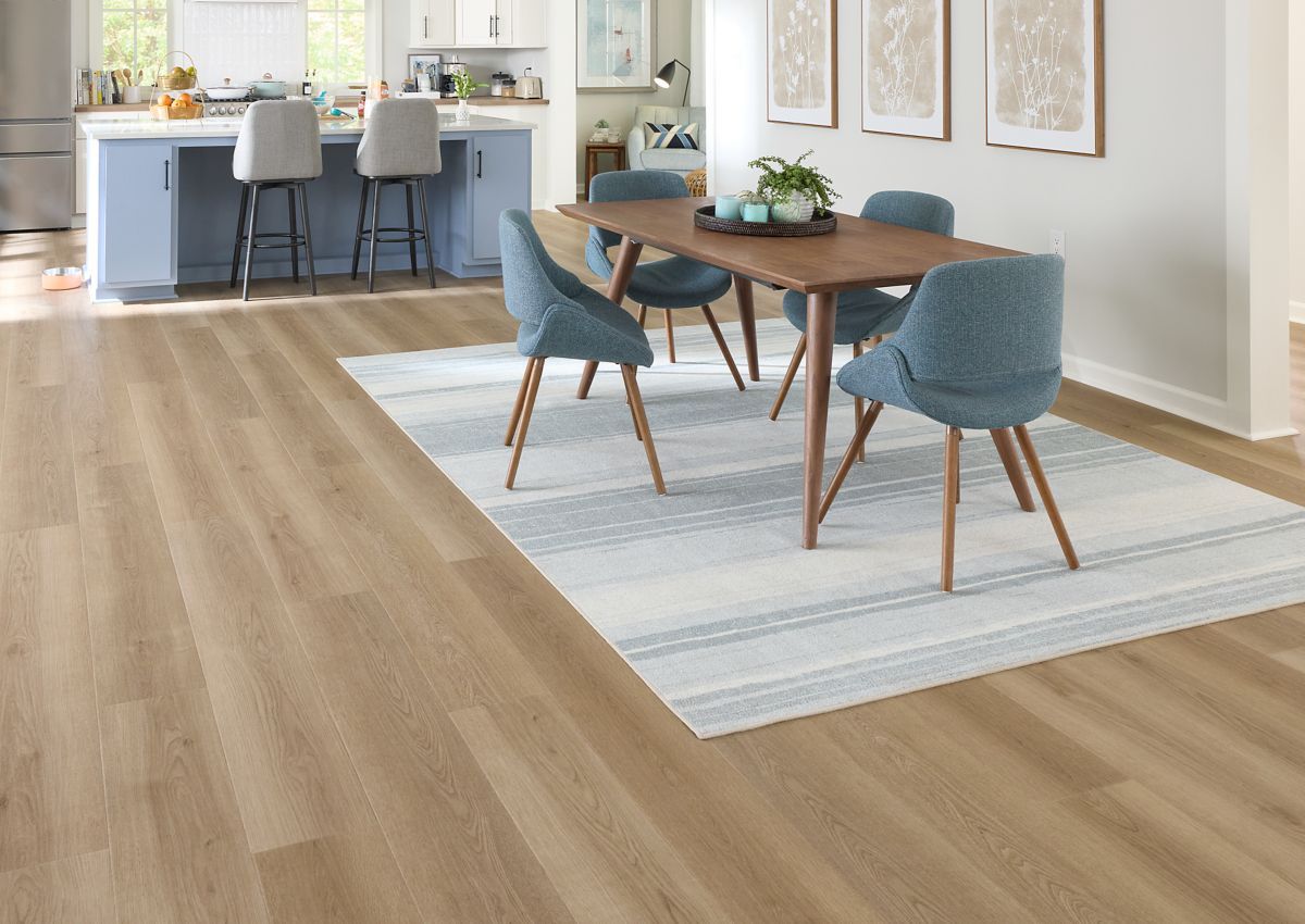 Dining area with wood flooring, table, blue chairs, and a patterned rug.