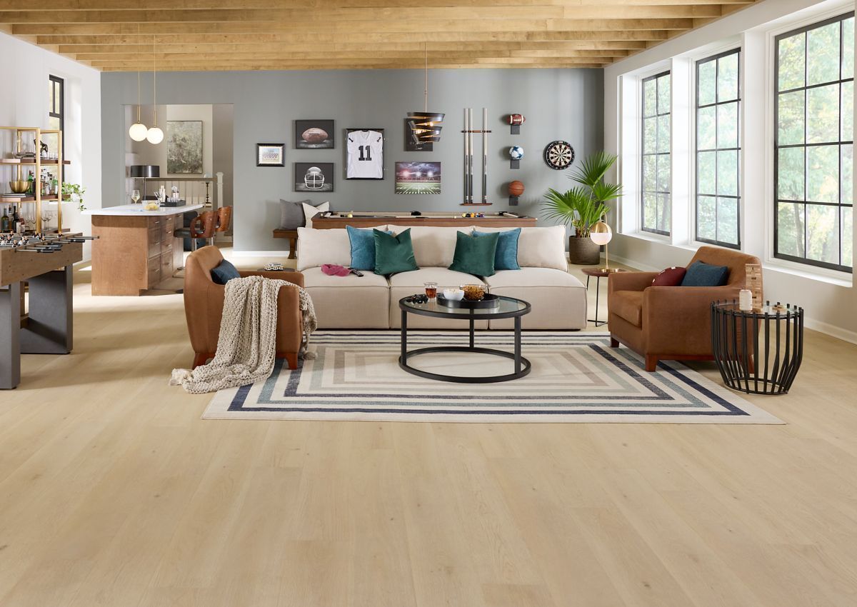 Living room with light wood floors, neutral sofa, leather chairs, and large windows.