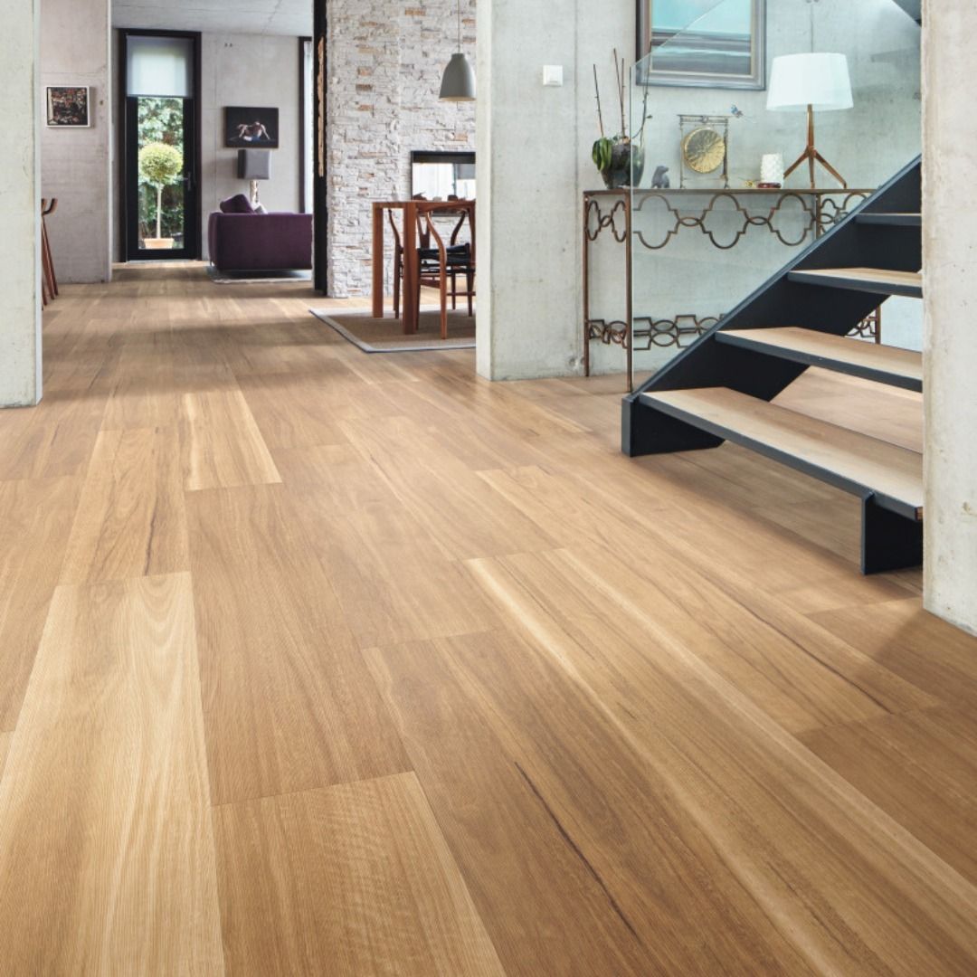 Light wood flooring in a home, leading to a living area and staircase.