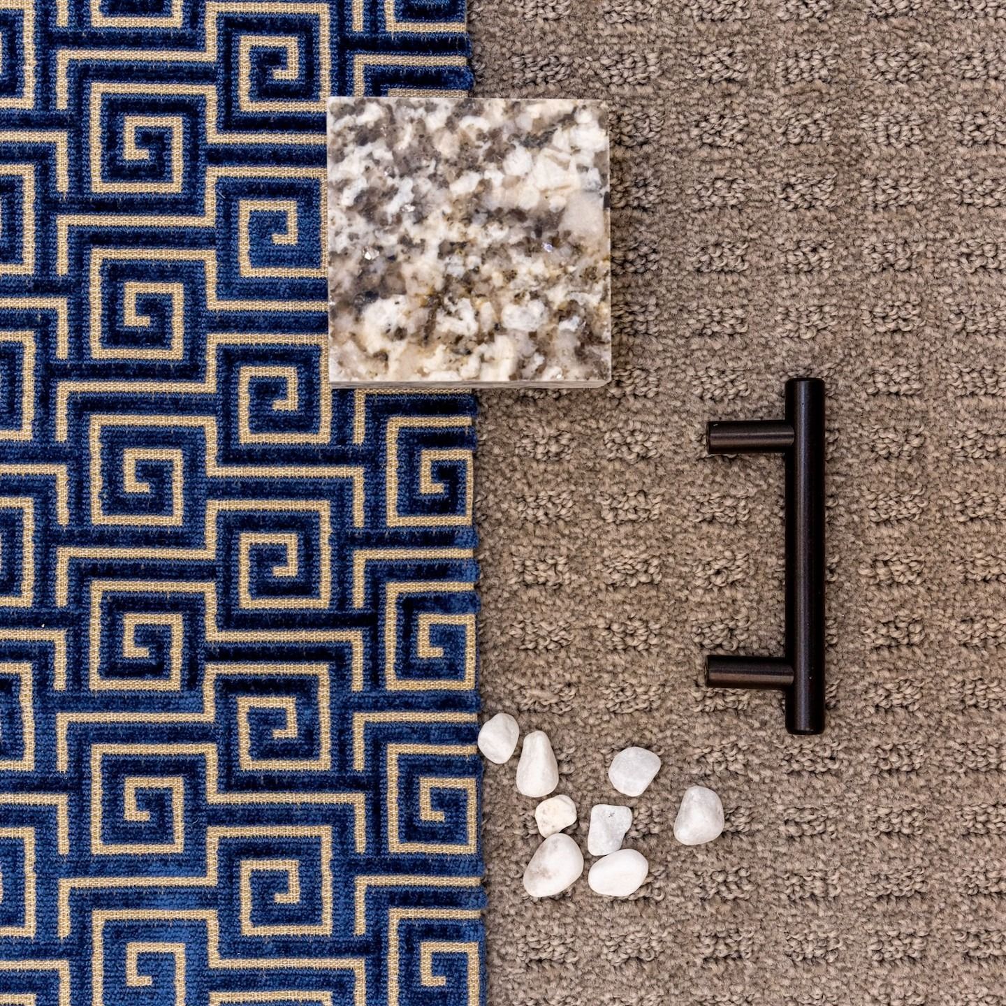 Blue patterned fabric, granite square, black handle, beige carpet, and white stones.