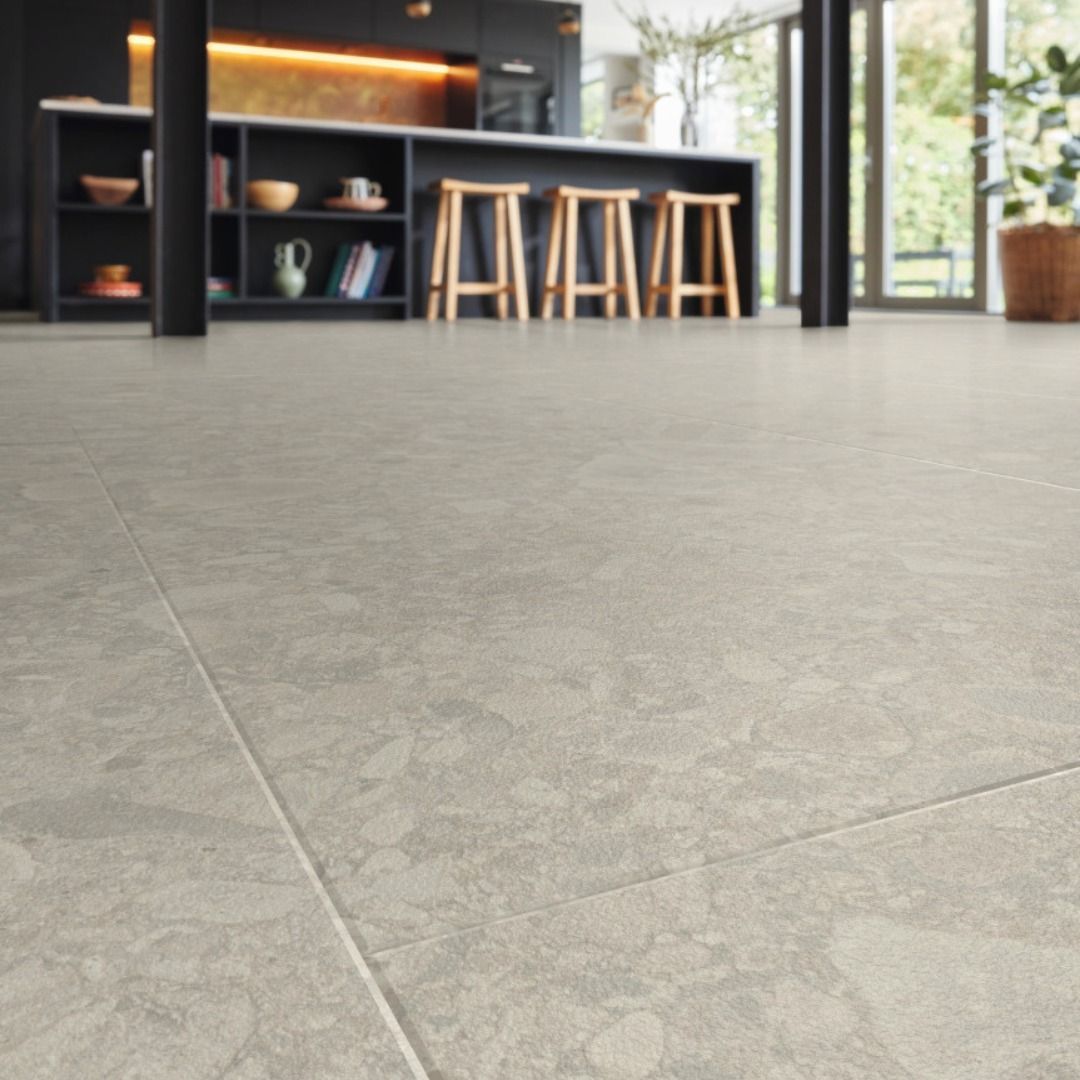 Light gray tiled floor in a kitchen with a bar, stools, and open doorway to a sunny outdoor area.