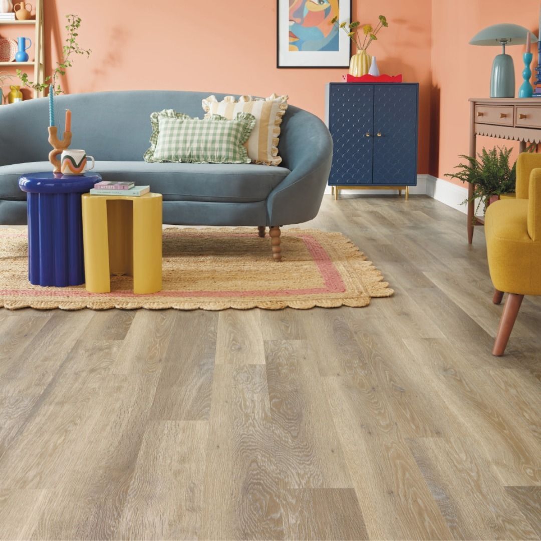 Living room with blue sofa, yellow armchair, wooden floor, colorful furniture, and coral wall.