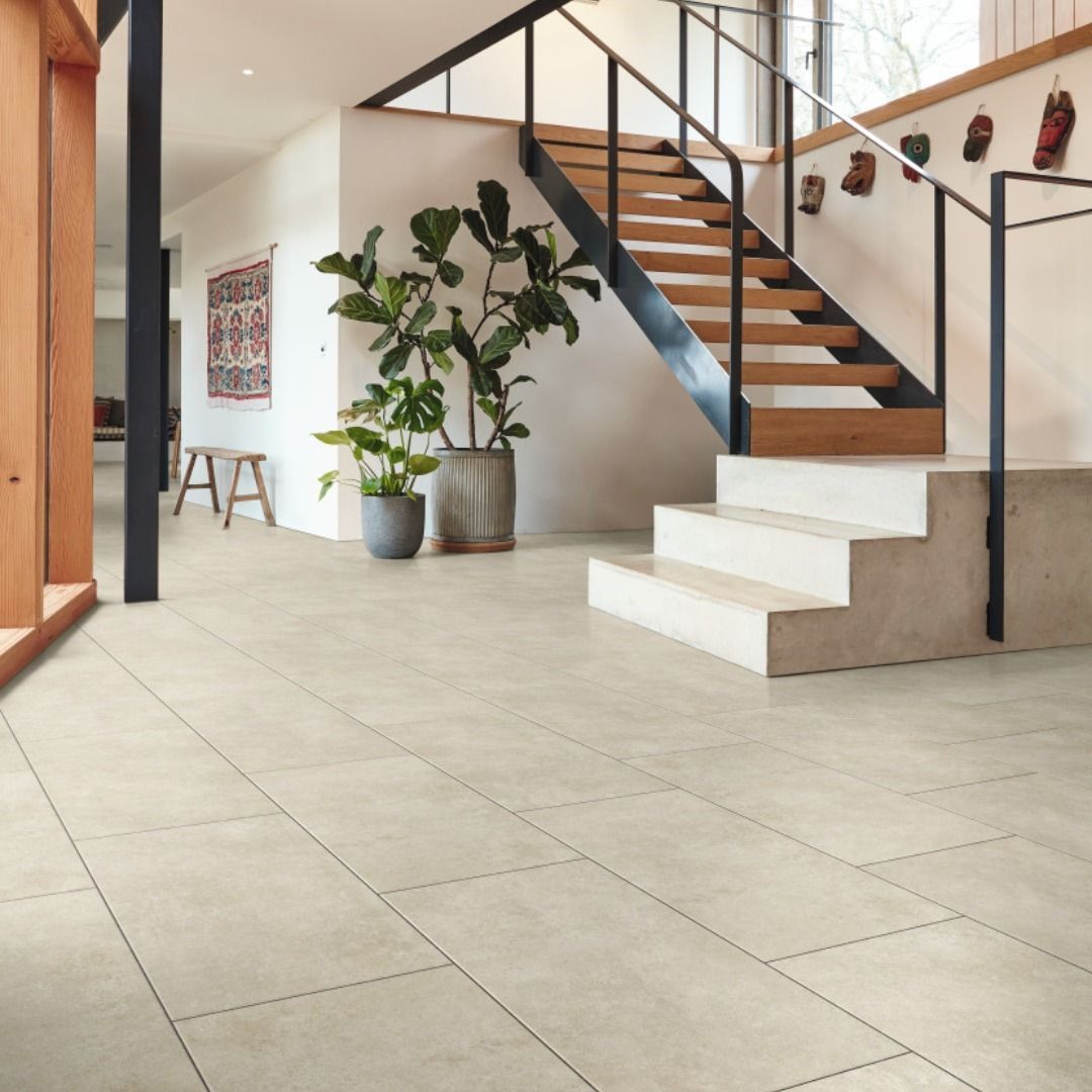 Beige tiled entry hall with staircase, plants, and natural light.