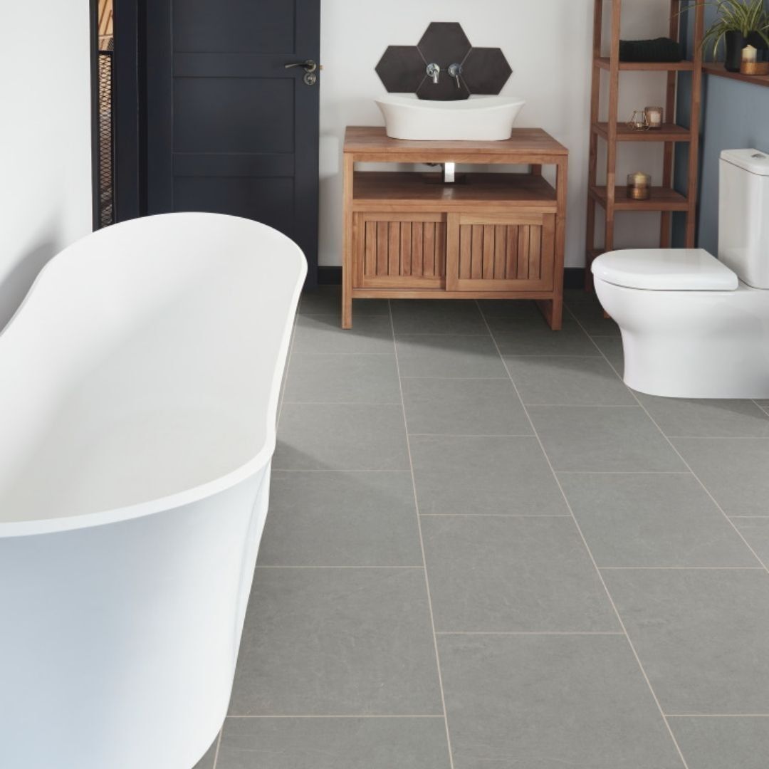Bathroom with a white clawfoot tub, gray tiled floor, wooden vanity, and toilet.